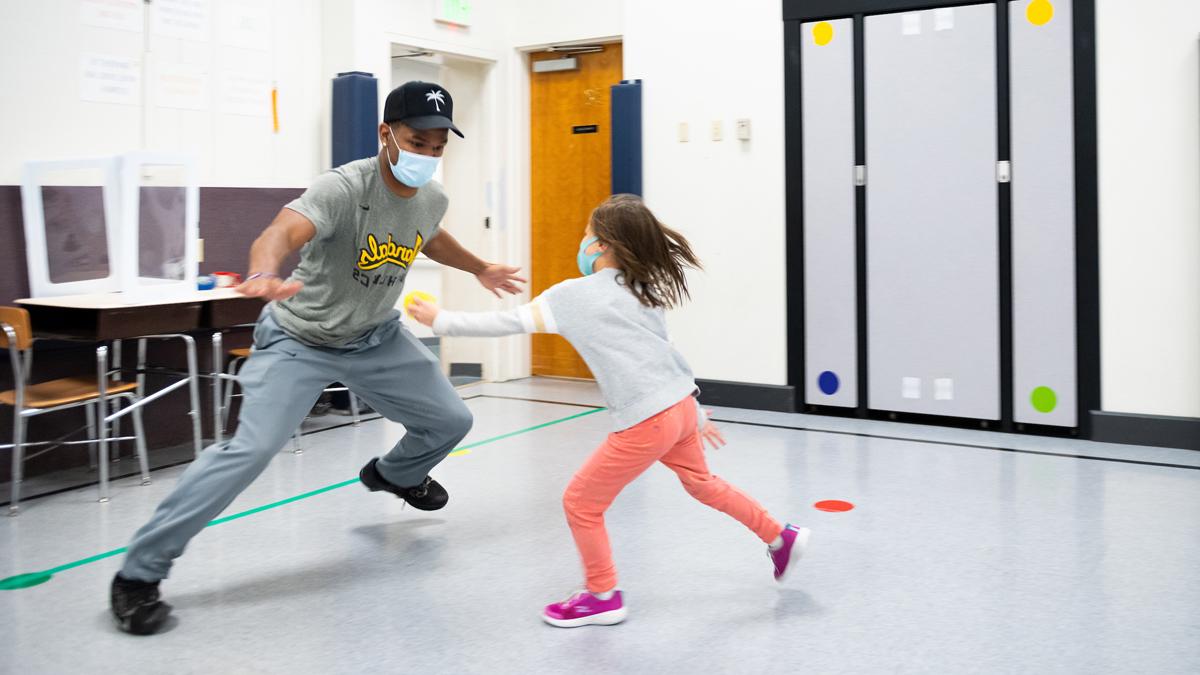 Vandal defensive back Wyryor Noil plays a game with a young girl in a Lena